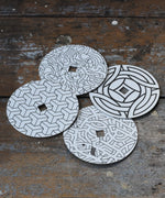 Mader patterned and coloured cardboard discs for 'So And So' Spinning Top placed on a wooden surface in the Babipur playroom. 