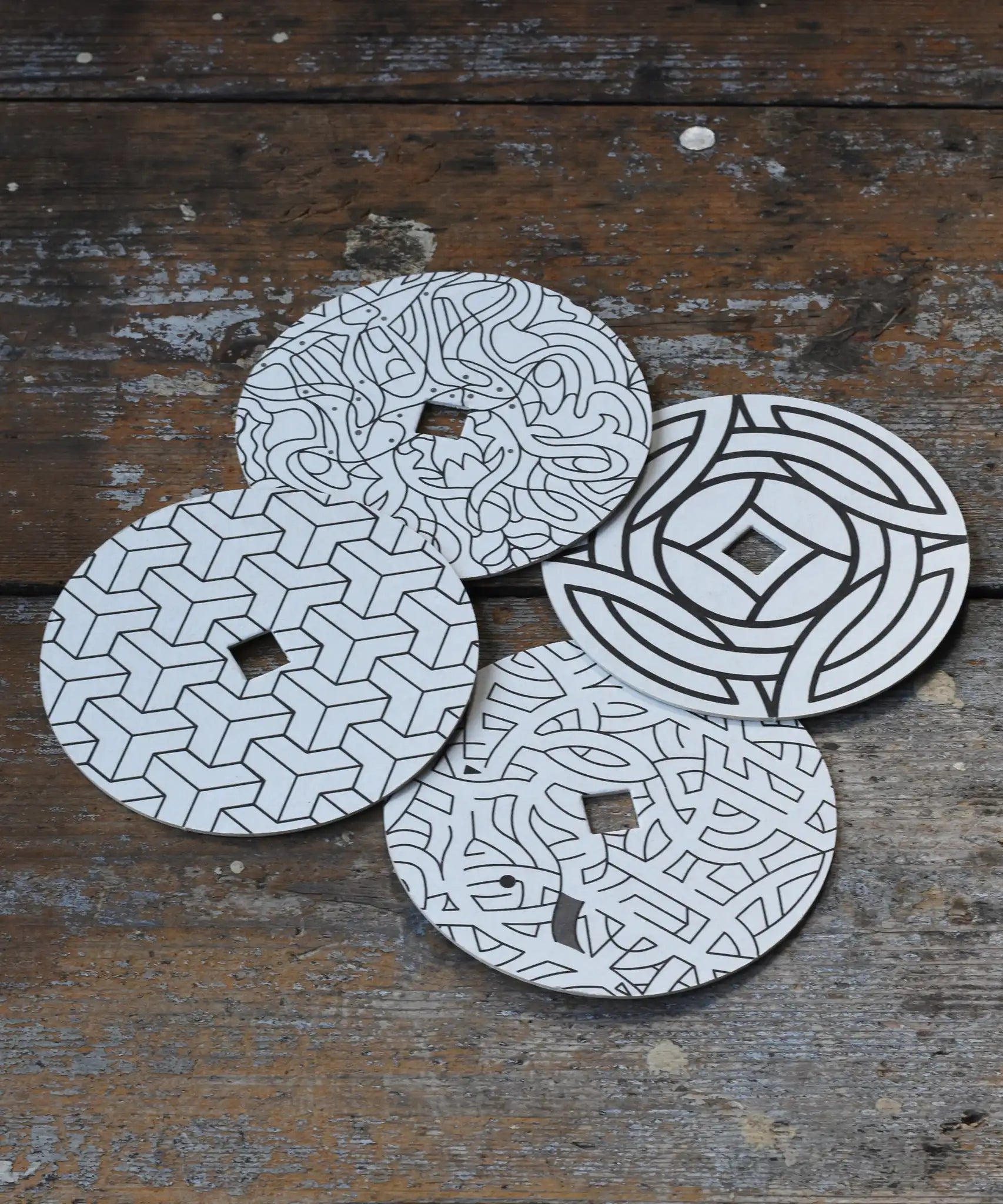 Mader patterned and coloured cardboard discs for 'So And So' Spinning Top placed on a wooden surface in the Babipur playroom. 