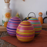 A collection of three Mader Kreiselmanufaktur roly-poly wooden eggs placed on a wooden surface in the Babipur playroom.
