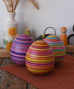 A collection of three Mader Kreiselmanufaktur roly-poly wooden eggs placed on a wooden surface in the Babipur playroom.