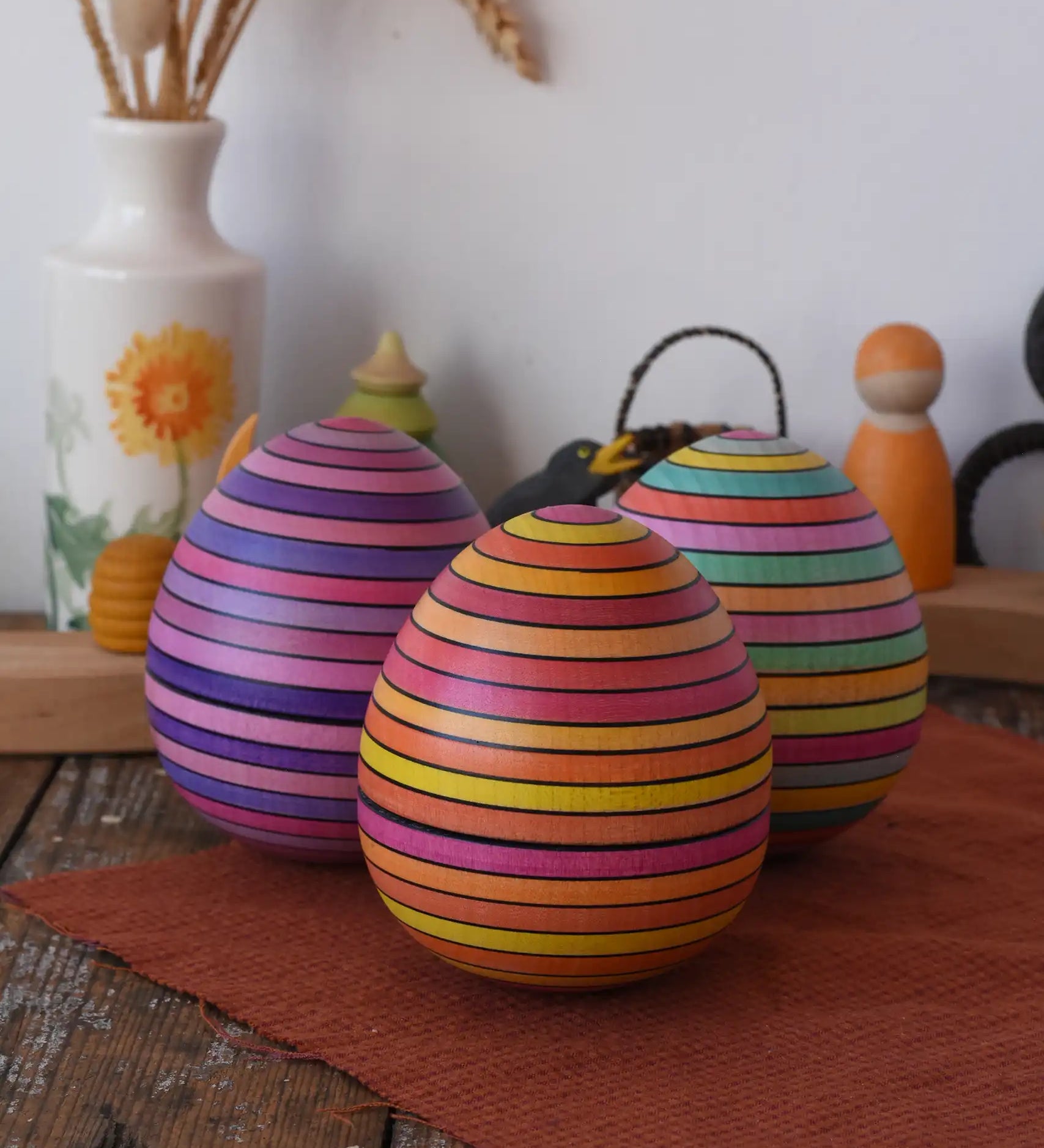 A collection of three Mader Kreiselmanufaktur roly-poly wooden eggs placed on a wooden surface in the Babipur playroom.