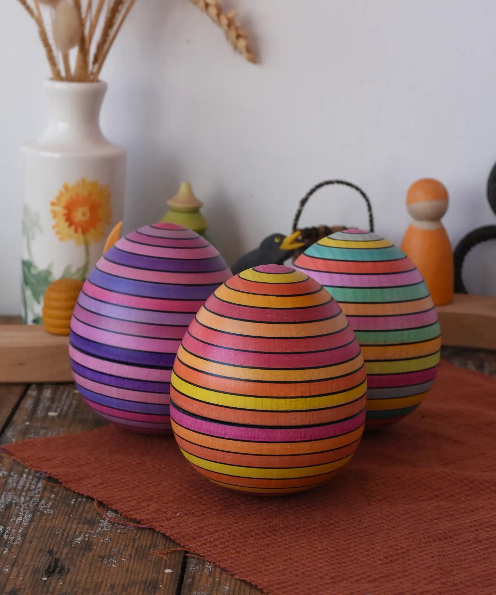 A collection of three Mader Kreiselmanufaktur roly-poly wooden eggs placed on a wooden surface in the Babipur playroom.