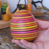 Mader Kreiselmanufaktur roly-poly wooden egg in Fire in an adult's hand.