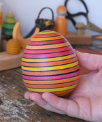 Mader Kreiselmanufaktur roly-poly wooden egg in Fire in an adult's hand.