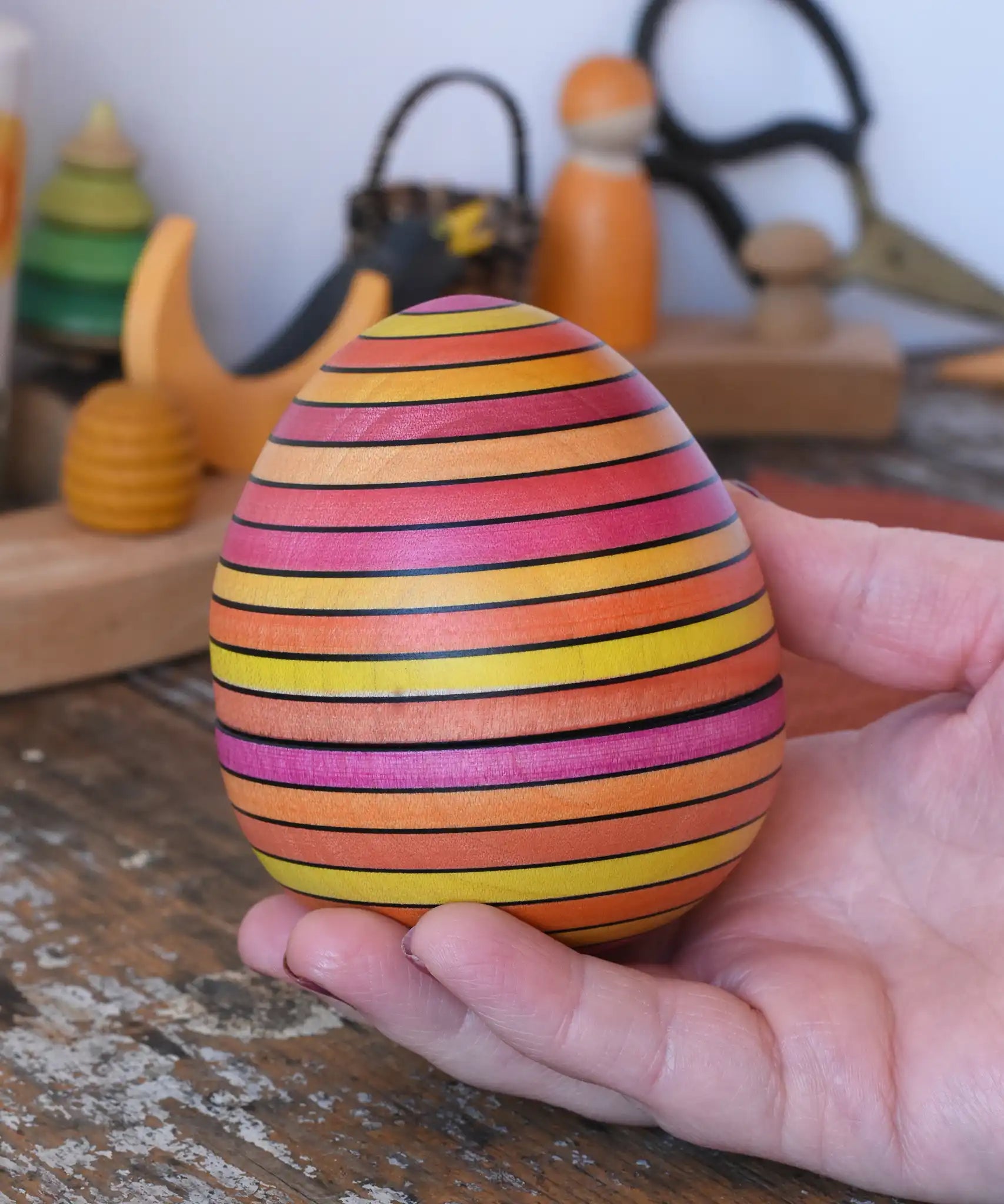 Mader Kreiselmanufaktur roly-poly wooden egg in Fire in an adult's hand.