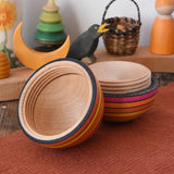 Mader Kreiselmanufaktur roly-poly wooden egg in fire opened and placed on a wooden surface in the Babipur playroom. The wooden thread can be seen on the sides of the egg.