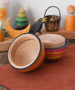 Mader Kreiselmanufaktur roly-poly wooden egg in fire opened and placed on a wooden surface in the Babipur playroom. The wooden thread can be seen on the sides of the egg.