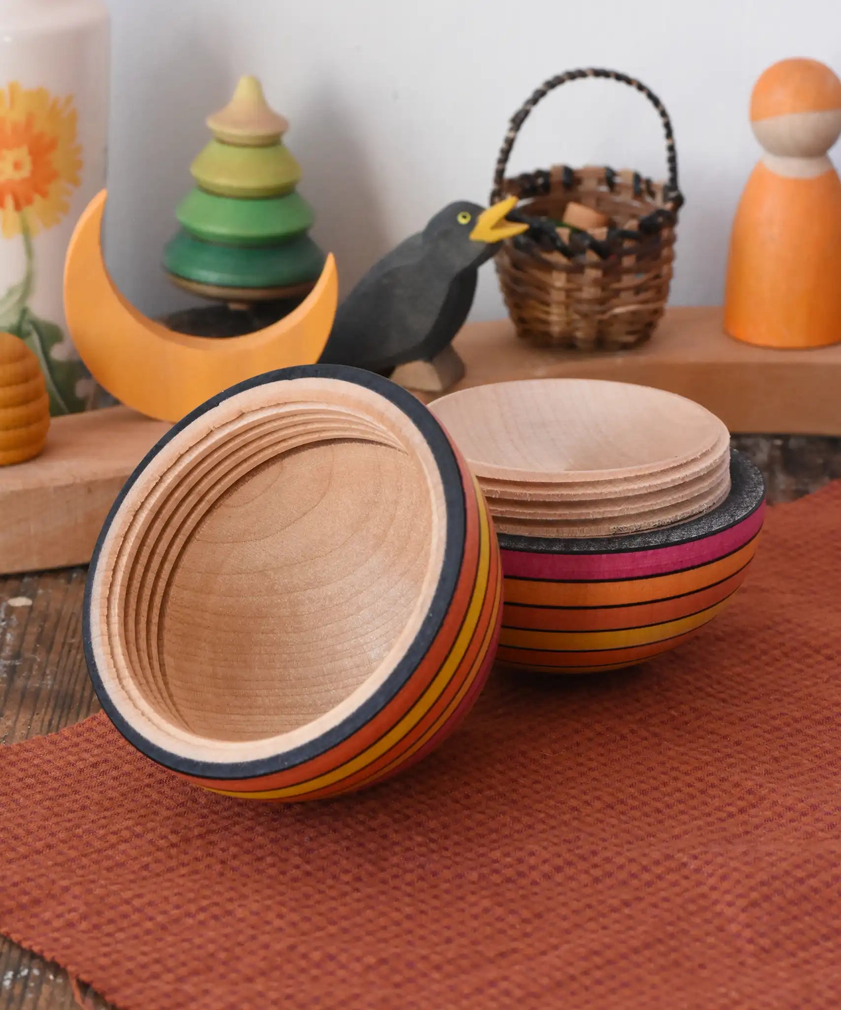 Mader Kreiselmanufaktur roly-poly wooden egg in fire opened and placed on a wooden surface in the Babipur playroom. The wooden thread can be seen on the sides of the egg.