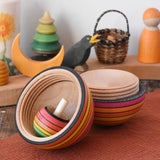 Mader Kreiselmanufaktur roly-poly wooden egg in fire opened with a rainbow turn-over spinning top placed inside in the Babipur playroom.