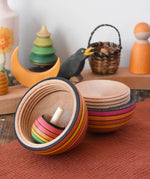 Mader Kreiselmanufaktur roly-poly wooden egg in fire opened with a rainbow turn-over spinning top placed inside in the Babipur playroom.
