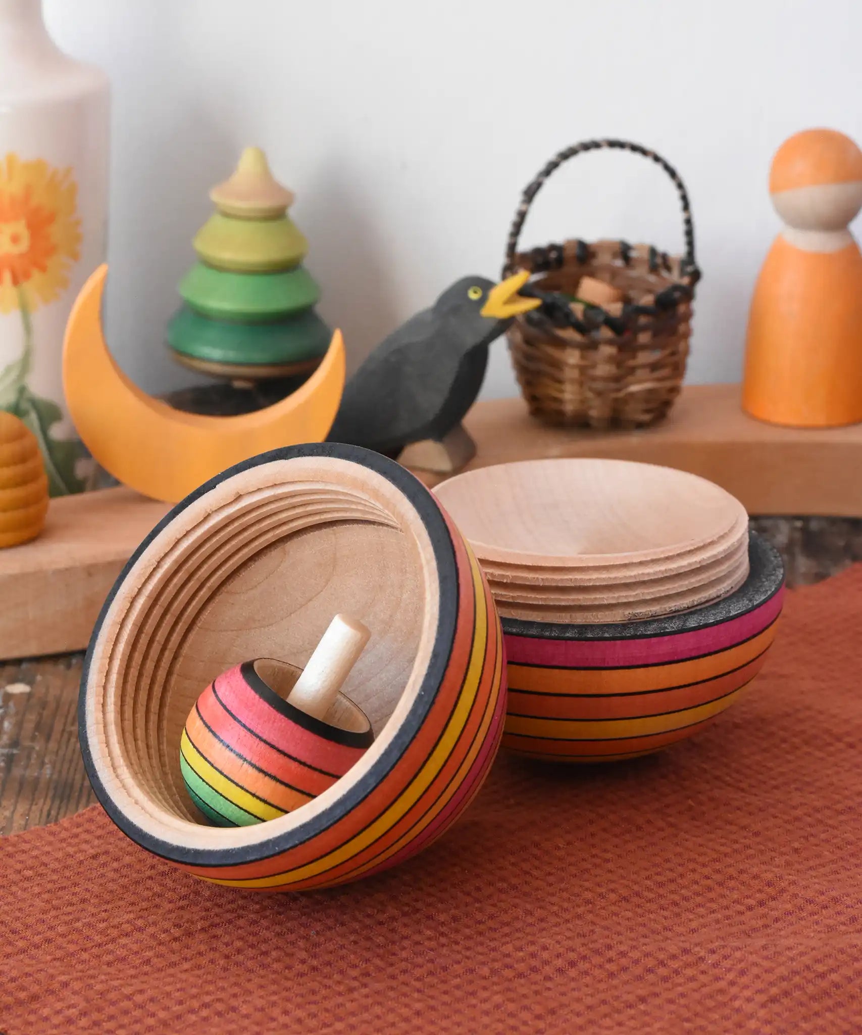 Mader Kreiselmanufaktur roly-poly wooden egg in fire opened with a rainbow turn-over spinning top placed inside in the Babipur playroom.