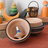 Mader Kreiselmanufaktur roly-poly wooden egg in graphite opened with a rainbow rallye spinning top placed inside in the Babipur playroom.