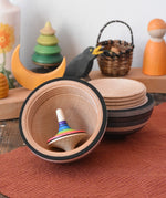 Mader Kreiselmanufaktur roly-poly wooden egg in graphite opened with a rainbow rallye spinning top placed inside in the Babipur playroom.