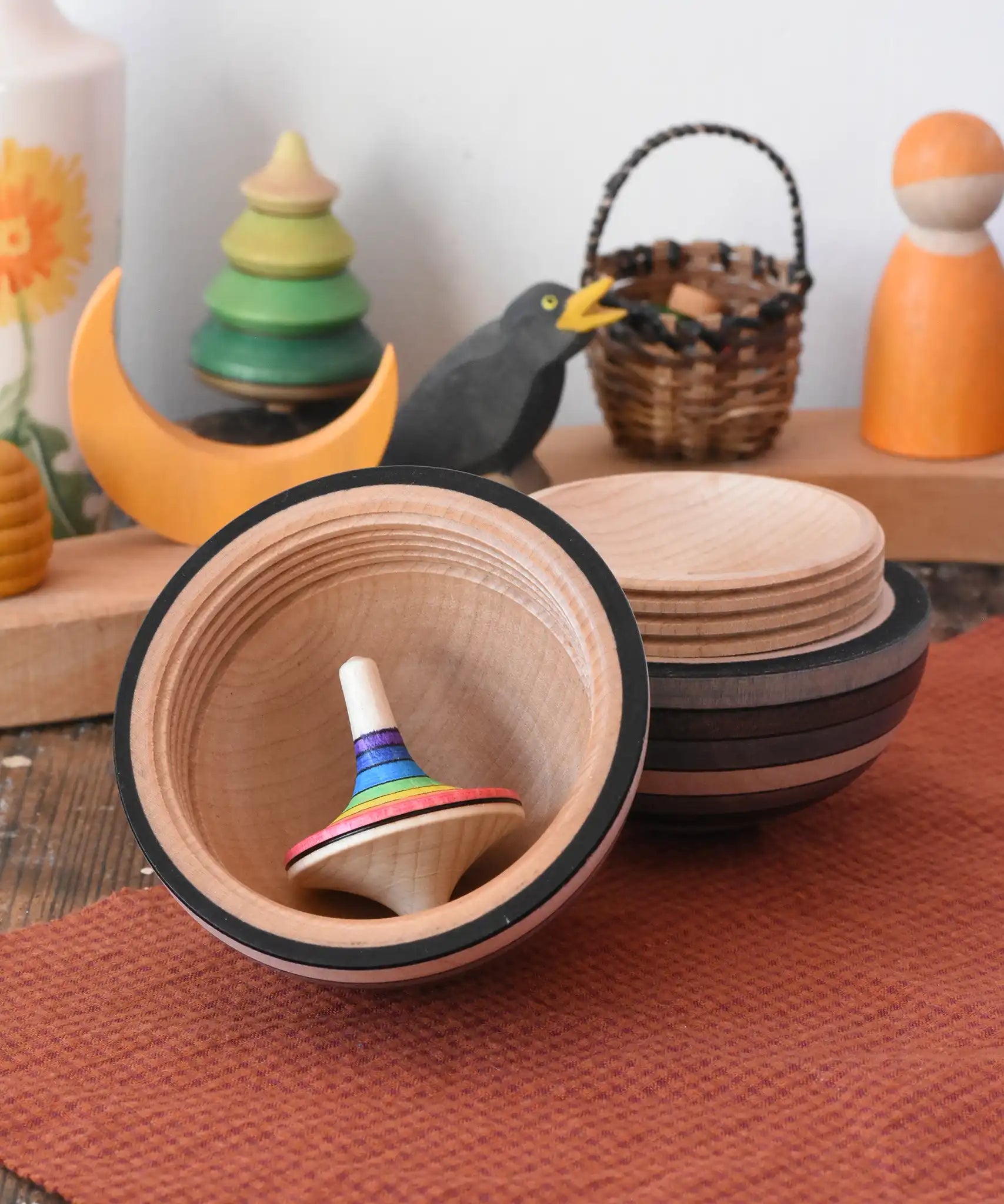 Mader Kreiselmanufaktur roly-poly wooden egg in graphite opened with a rainbow rallye spinning top placed inside in the Babipur playroom.