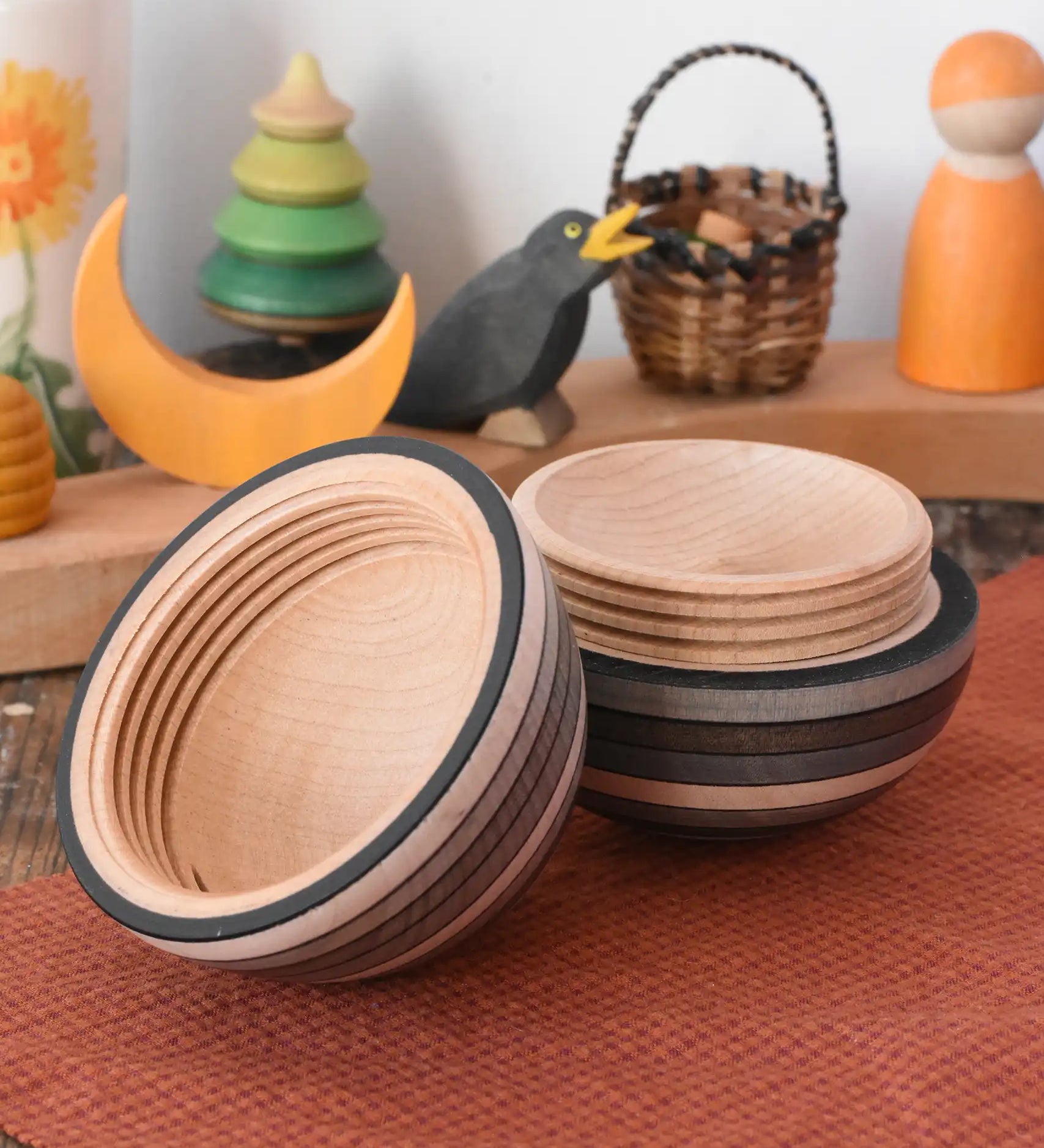 Mader Kreiselmanufaktur roly-poly wooden egg in graphite opened and placed on a wooden surface in the Babipur playroom. The wooden thread can be seen on the sides of the egg.