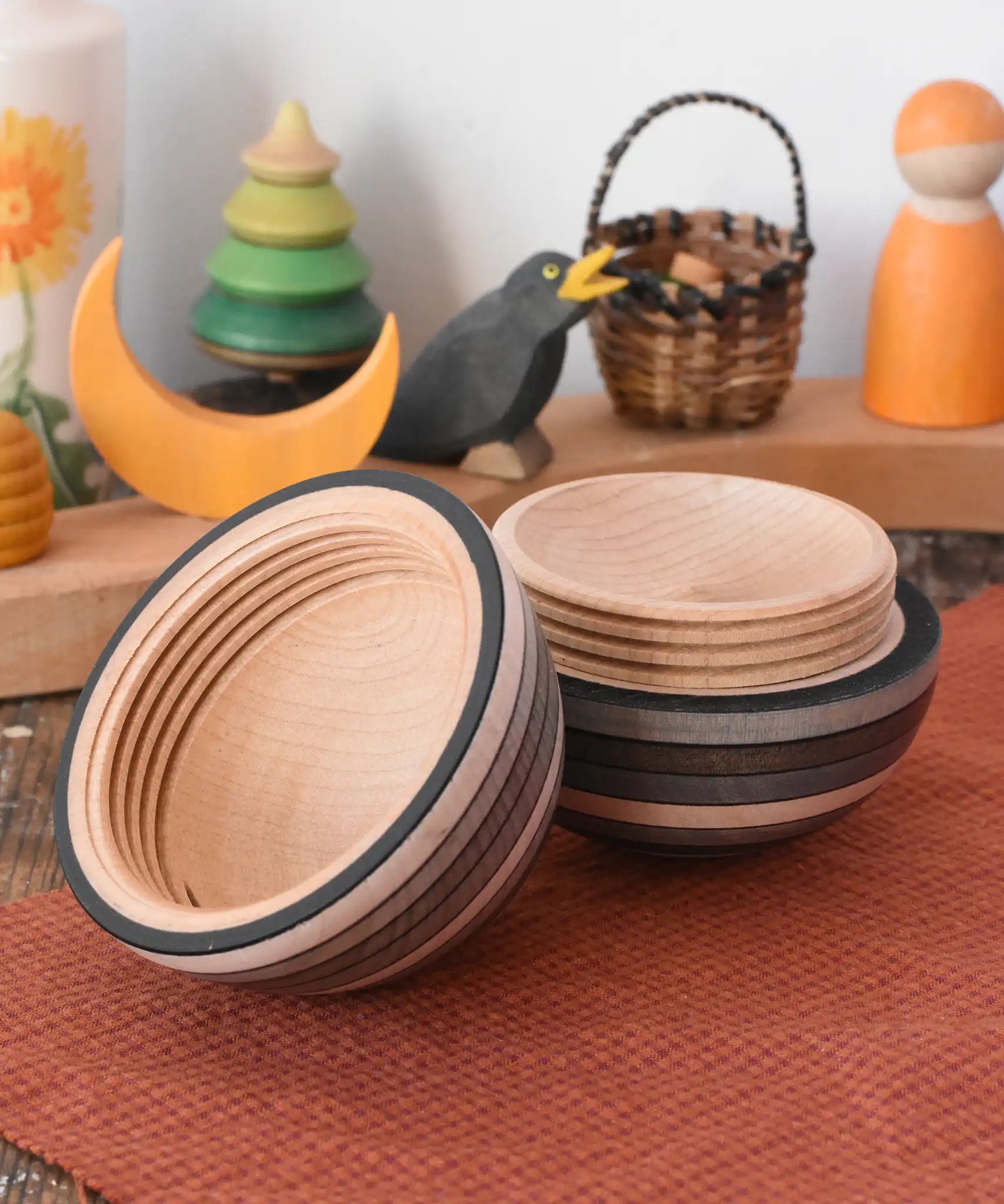 Mader Kreiselmanufaktur roly-poly wooden egg in graphite opened and placed on a wooden surface in the Babipur playroom. The wooden thread can be seen on the sides of the egg.