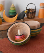 Mader Kreiselmanufaktur roly-poly wooden egg in green opened with a rainbow turn-over spinning top placed inside in the Babipur playroom.