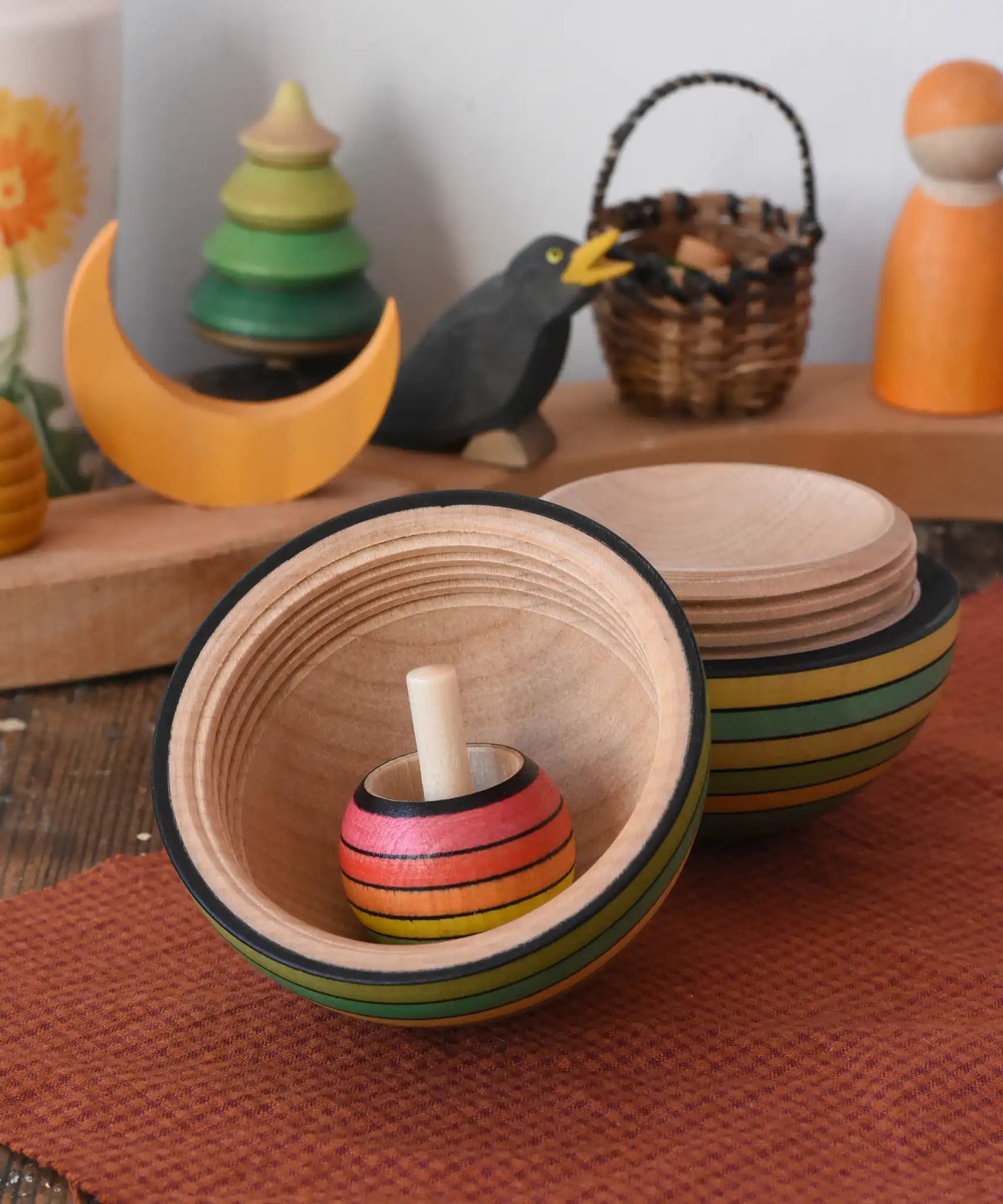 Mader Kreiselmanufaktur roly-poly wooden egg in green opened with a rainbow turn-over spinning top placed inside in the Babipur playroom.