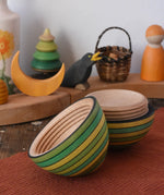Mader Kreiselmanufaktur roly-poly wooden egg in green opened and placed on a wooden surface in the Babipur playroom. The wooden thread can be seen on the sides of the egg.