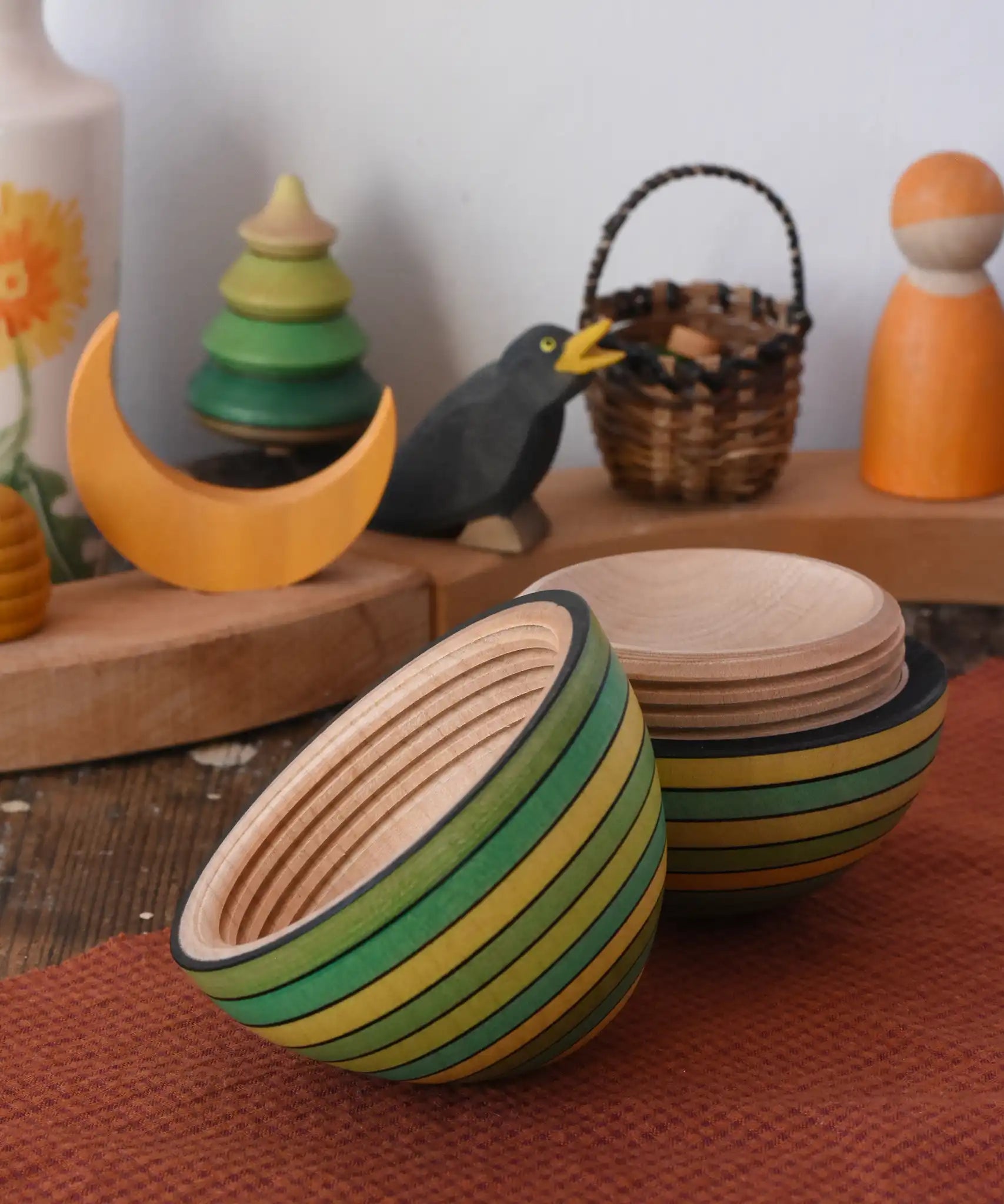 Mader Kreiselmanufaktur roly-poly wooden egg in green opened and placed on a wooden surface in the Babipur playroom. The wooden thread can be seen on the sides of the egg.