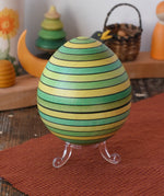Mader Kreiselmanufaktur roly-poly wooden egg in green placed on the clear display stand in the Babipur playroom.