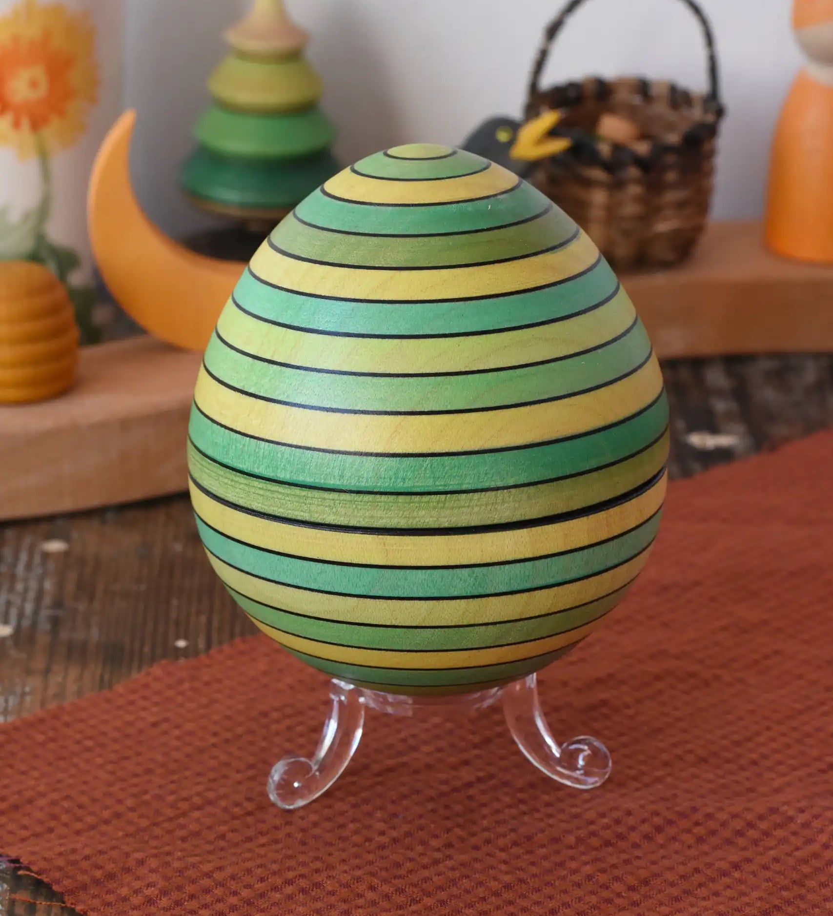 Mader Kreiselmanufaktur roly-poly wooden egg in green placed on the clear display stand in the Babipur playroom.