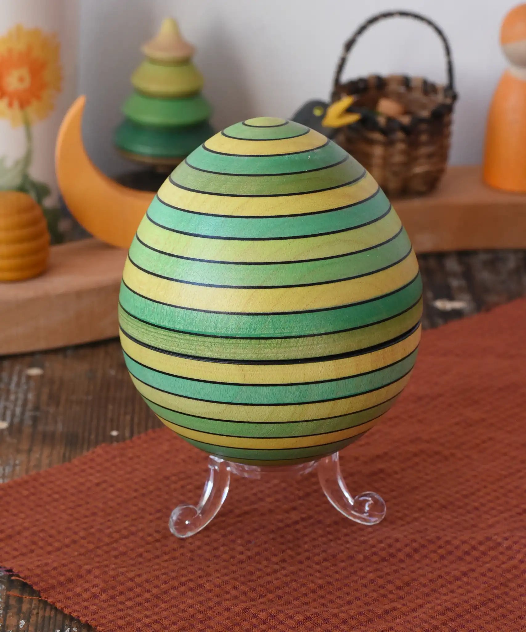 Mader Kreiselmanufaktur roly-poly wooden egg in green placed on the clear display stand in the Babipur playroom.
