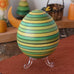 Mader Kreiselmanufaktur roly-poly wooden egg in green placed on the clear display stand in the Babipur playroom.