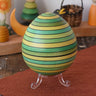 Mader Kreiselmanufaktur roly-poly wooden egg in green placed on the clear display stand in the Babipur playroom.