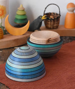 Mader Kreiselmanufaktur roly-poly wooden egg in ice blue opened and placed on a wooden surface in the Babipur playroom. The wooden thread can be seen on the sides of the egg.