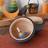 Mader Kreiselmanufaktur roly-poly wooden egg in ice blue stripes opened with a rainbow rallye spinning top placed inside in the Babipur playroom.