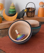 Mader Kreiselmanufaktur roly-poly wooden egg in ice blue stripes opened with a rainbow rallye spinning top placed inside in the Babipur playroom.