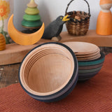 Mader Kreiselmanufaktur roly-poly wooden egg in ice blue opened and placed on a wooden surface in the Babipur playroom. The wooden thread can be seen on the sides of the egg.