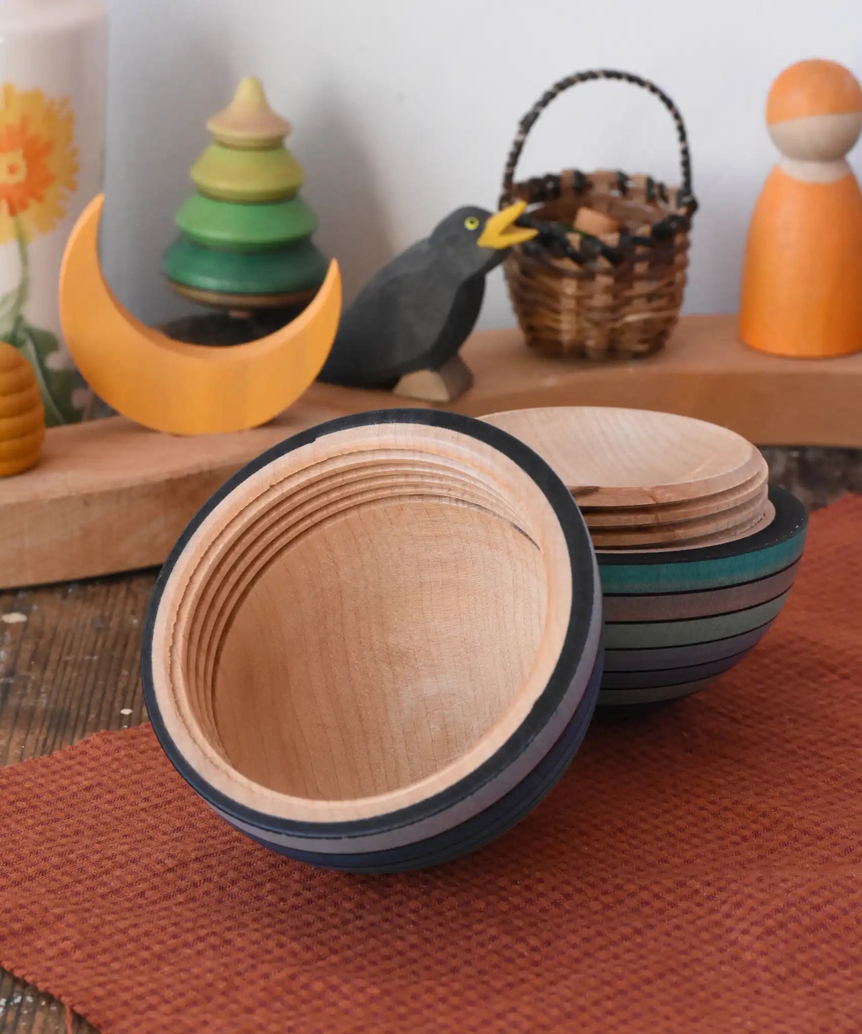 Mader Kreiselmanufaktur roly-poly wooden egg in ice blue opened and placed on a wooden surface in the Babipur playroom. The wooden thread can be seen on the sides of the egg.