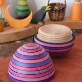 Mader Kreiselmanufaktur roly-poly wooden egg in lilac opened and placed on a wooden surface in the Babipur playroom. The wooden thread can be seen on the sides of the egg.