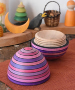 Mader Kreiselmanufaktur roly-poly wooden egg in lilac opened and placed on a wooden surface in the Babipur playroom. The wooden thread can be seen on the sides of the egg.