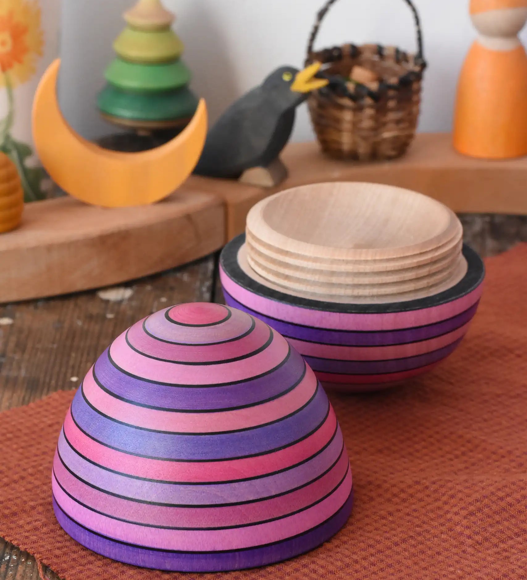 Mader Kreiselmanufaktur roly-poly wooden egg in lilac opened and placed on a wooden surface in the Babipur playroom. The wooden thread can be seen on the sides of the egg.