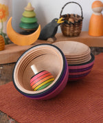 Mader Kreiselmanufaktur roly-poly wooden egg in graphite opened with a rainbow turn-over spinning top placed inside in the Babipur playroom.
