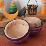 Mader Kreiselmanufaktur roly-poly wooden egg in lilac opened and placed on a wooden surface in the Babipur playroom. The wooden thread can be seen on the sides of the egg.