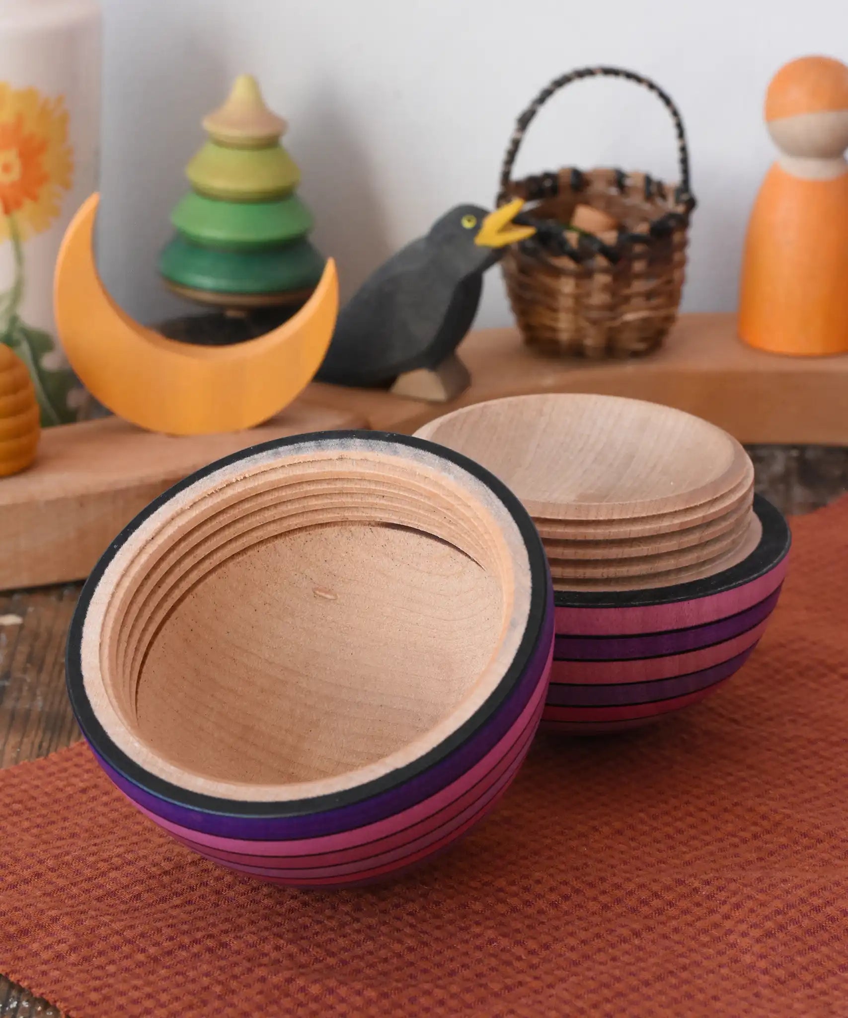 Mader Kreiselmanufaktur roly-poly wooden egg in lilac opened and placed on a wooden surface in the Babipur playroom. The wooden thread can be seen on the sides of the egg.