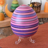 Mader Kreiselmanufaktur roly-poly wooden egg in lilac placed on the clear display stand in the Babipur playroom.