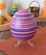 Mader Kreiselmanufaktur roly-poly wooden egg in lilac placed on the clear display stand in the Babipur playroom.