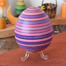 Mader Kreiselmanufaktur roly-poly wooden egg in lilac placed on the clear display stand in the Babipur playroom.