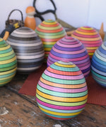 Mader Kreiselmanufaktur roly-poly wooden egg in Spring placed on a wooden surface in the Babipur playroom. Other colour ways of the egg can be seen in the background.