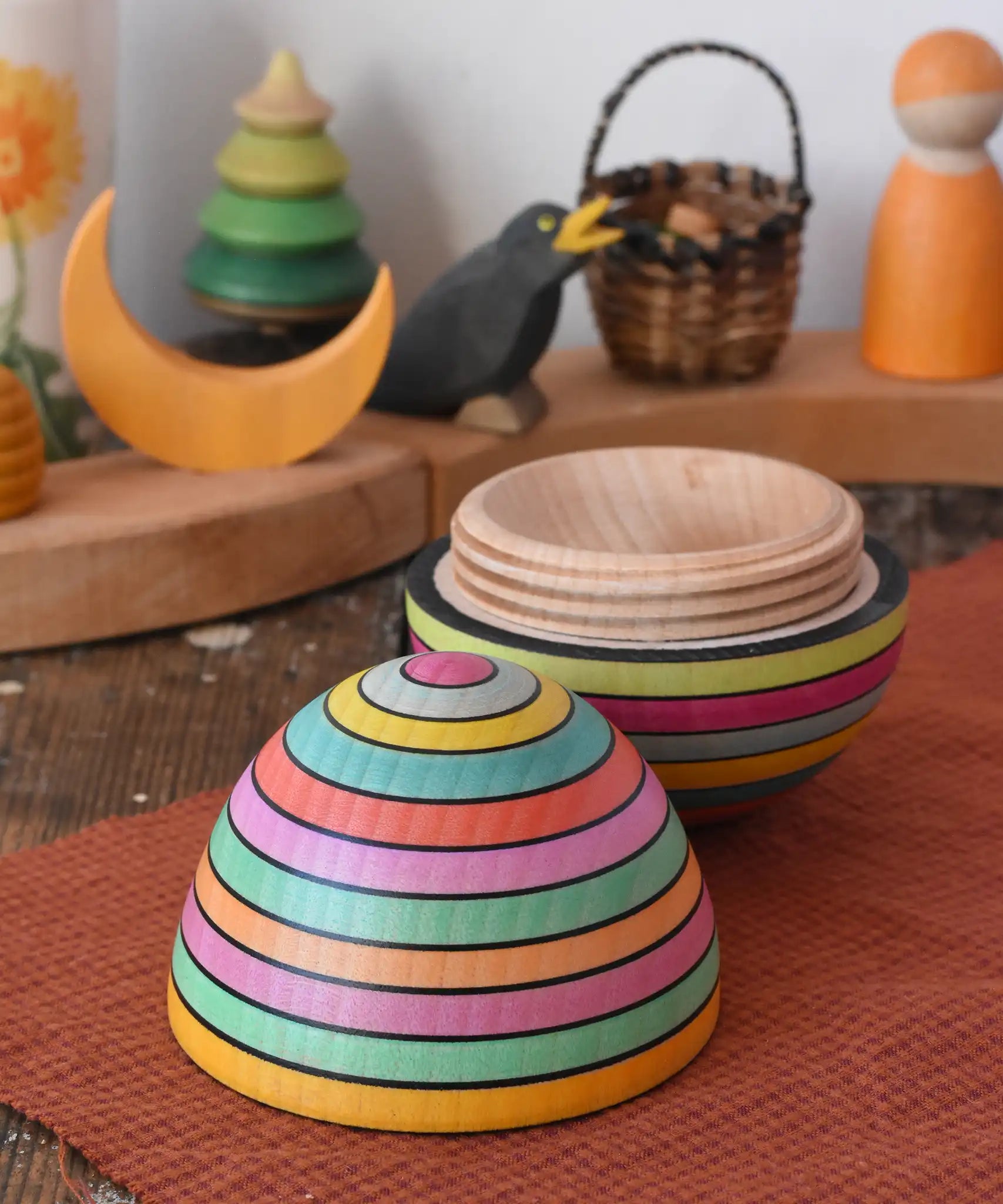 Mader Kreiselmanufaktur roly-poly wooden egg in Spring opened and placed on a wooden surface in the Babipur playroom. The wooden thread can be seen on the sides of the egg.