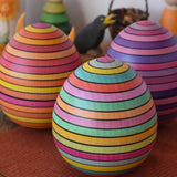 Mader Kreiselmanufaktur roly-poly wooden egg in Spring placed on a wooden surface in the Babipur playroom. Lilac and fire colour ways of the egg can be seen in the background.