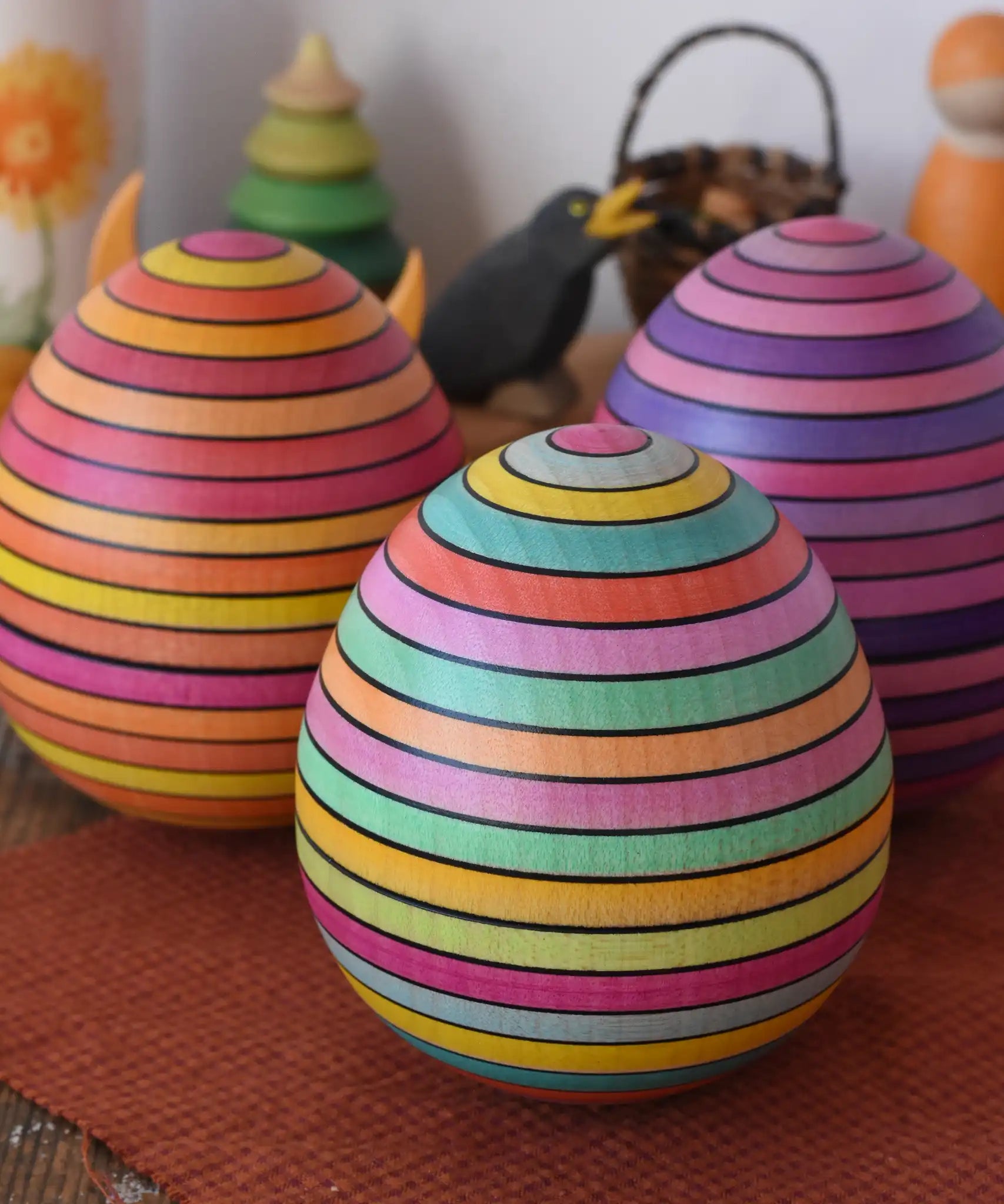 Mader Kreiselmanufaktur roly-poly wooden egg in Spring placed on a wooden surface in the Babipur playroom. Lilac and fire colour ways of the egg can be seen in the background.