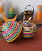 Mader Kreiselmanufaktur roly-poly wooden egg in Spring opened with a rainbow rallye spinning top placed inside in the Babipur playroom.