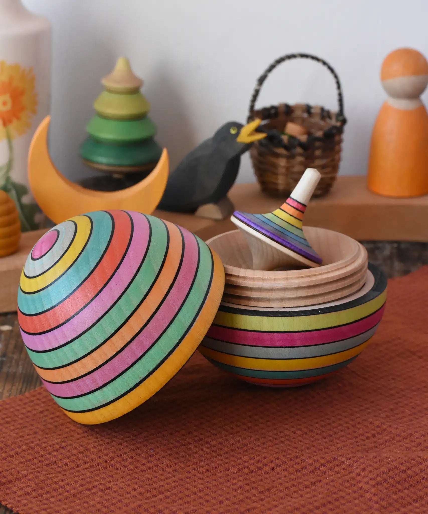 Mader Kreiselmanufaktur roly-poly wooden egg in Spring opened with a rainbow rallye spinning top placed inside in the Babipur playroom.