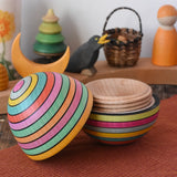 Mader Kreiselmanufaktur roly-poly wooden egg in Spring opened and placed on a wooden surface in the Babipur playroom. The wooden thread can be seen on the sides of the egg.